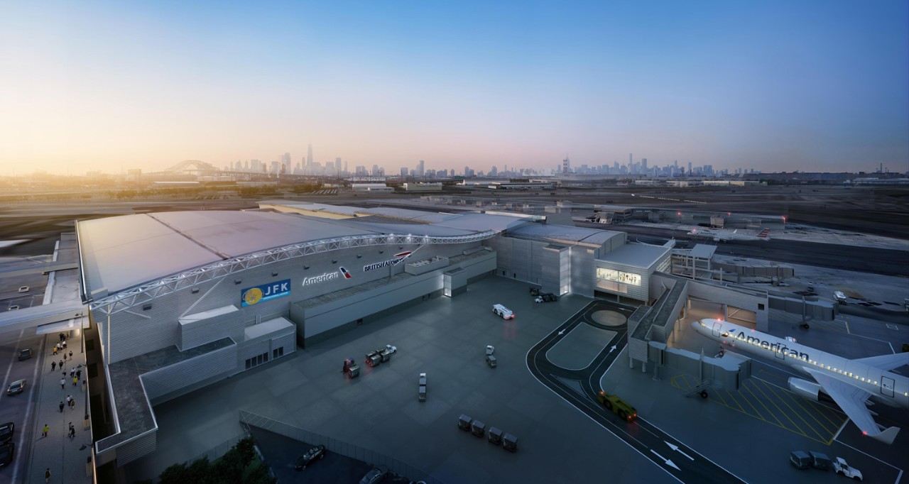 Aerial view of JFK Airport showing the American Airlines terminal with a city skyline in the background at dusk.