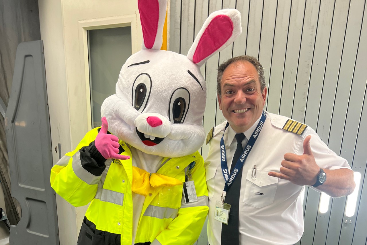 A pilot smiles next to a person in an Easter bunny costume