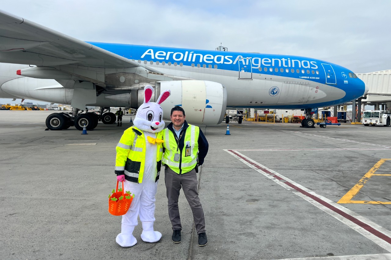 A man smiles with the Easter Bunny in front of an airplane