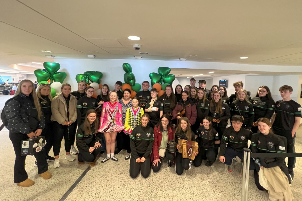 A group of people including dancers in traditional Irish gear celebrate St. Patrick's Day at Terminal 7