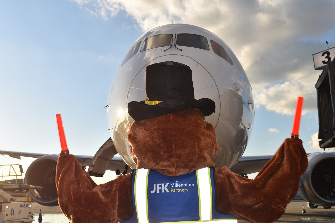 Person in a turkey costume stands in front of an airplane