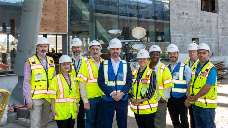 Group of JMP staff smiling at camera in construction jackets and hardhats