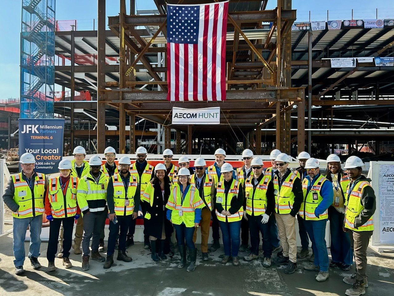Group of people in safety gear stand at construction site